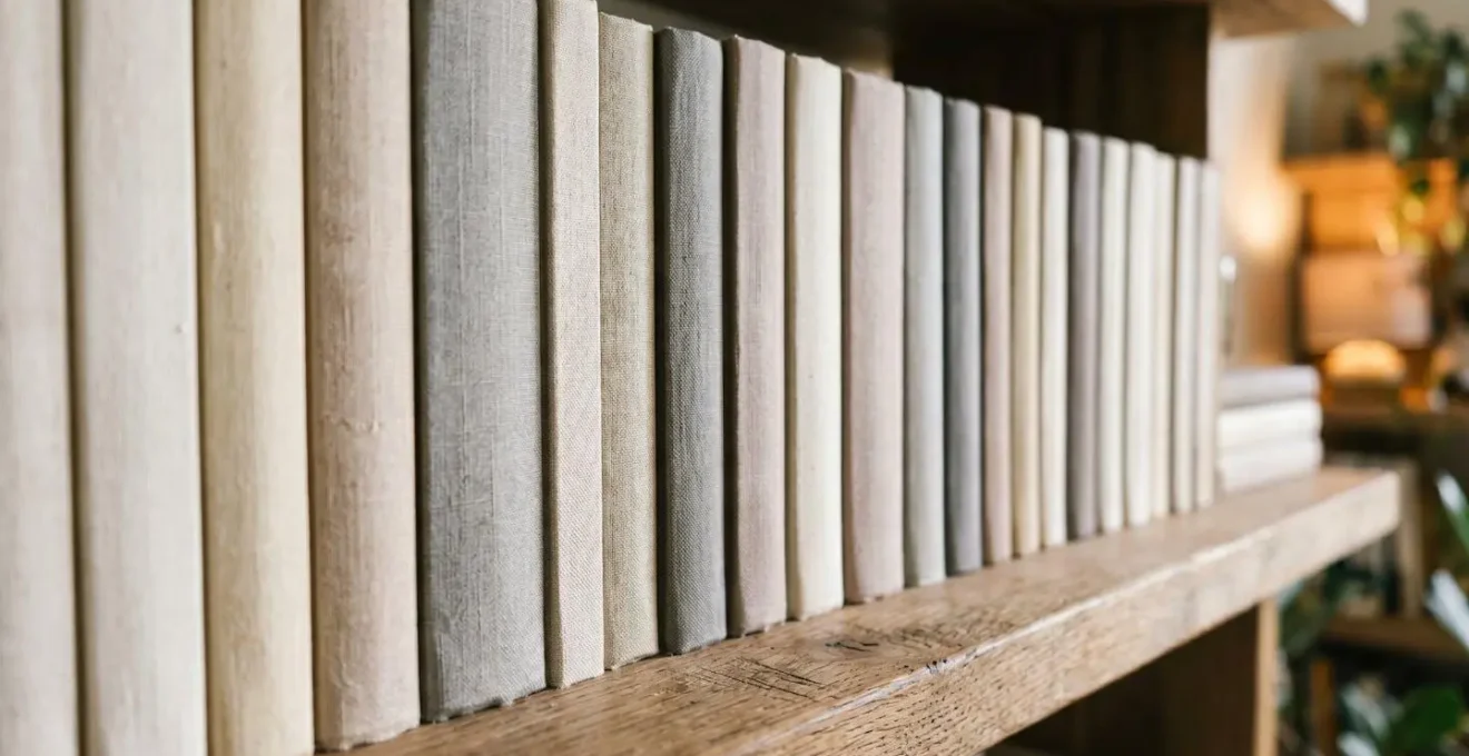 Étagère avec livres rangés de manière uniforme, dos neutres, créant un effet visuel apaisant